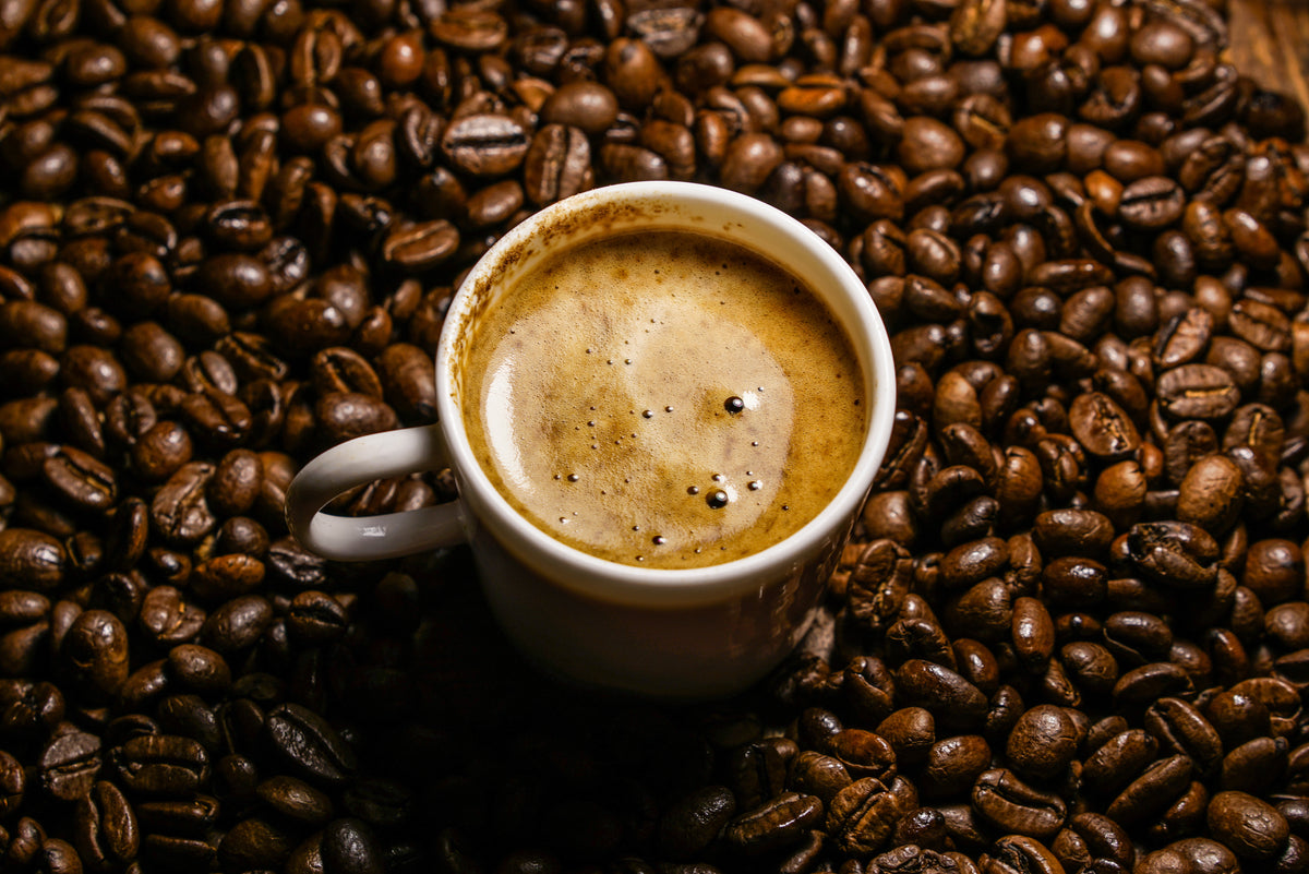 Cup of coffee on top of coffee beans